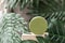 Round green cosmetic jar on podium and green tropical leaves around, natural cosmetic layout, selective focus