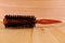 Round hairstyling brush isolated on wooden table.