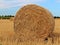 Round hay bale on stubble field harvest season landscape