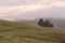 Round haystack on a sloping green field in cloudy weather