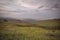 Round haystack on a sloping green field in cloudy weather