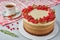 Round homemade cake decorated with red currants, figs, cinnamon and rosemary with tablecloth, Cup and saucer on a light background