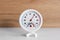 Round hygrometer with thermometer on white table, closeup