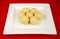 Round Indian laddu sweets on a white square plate