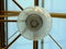 Round lantern on a pedestrian bridge with a transparent roof and blue sky, closeup and reflections