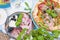 Round large pizza from the oven with prosciutto and olives, arugula and basil. Table setting for lunch or dinner. Table and