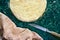 Round layered napoleon cake with custard and sprinkled crumbs, knife, towel and mixer on a green marble table, top view. The