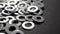 Round metallic fastening washers on a black paper. Metal steel chrome hardware