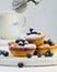 Round mini cottage cheese pies with blueberries on a white wooden board