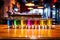 a round of multi-colored shots lined up on a bar