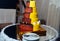 Round multi tiered yellow and brown wedding cake with strawberries, roses and chocolate icing. Plate and fork near the cake.