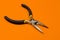 The round nose pliers on the orange background of copyspace. For electrician, jeweler and builder. Metal tool for
