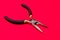 The round nose pliers on the red background of copyspace. For electrician, jeweler and builder. Metal tool for bending wire and