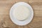 Round piece of cottage cheese in white plate on table