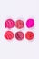 Round pieces of sliced lipstick in two rows on a white background. Colorful lipsticks. Isolated