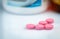 Round pink tablets pill on blurred drug bottle. Vitamins and minerals plus folic acid vitamin E and zinc in drug bottle