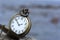 Round pocket watch with chain on stone on background of sky with