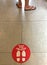 Round red sign for  Please keep your social distance` with footprint on floor makes caution for people que in line for 2 feet safe