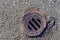 A round, rusty metal grate over a storm water drain