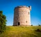 Round shaped, small, stone built, castle on plot of countryside land.