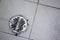 Round shower drain strainer made of stainless steel in a recently used shower.