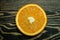 Round slice bright juicy ripe beautiful orange on a coarse dark wooden background from boards