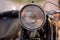 Round soviet headlight of retro motorcycle closeup beige background