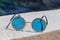 Round sunglasses with blue glasses on the stone.