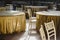 Round tables with tablecloths, empty, surrounded by wooden chairs, in a restaurant