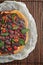 A round tart with berries in the wooden background