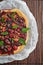 A round tart with berries in the wooden background