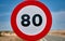 round traffic sign with red border and black limit number 80 km/h mph