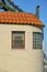 Round turret or spire style exterior wall with visible bay windows and a thin adobe orange roof with tiles and chimney