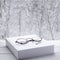 Round vintage reading glasses lie on a white thick notepad against the backdrop of the forest