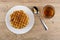 Round waffles in white plate, cup of tea and teaspoon