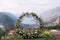 Round wedding arch stands on a mountain above the Bay of Kotor surrounded by a ridge in the fog