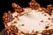 Round white cake with caramel and chocolate puffed rice on a round tray on black background