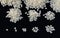 Round white grains of rice lie in exponentially increasing rice piles on a black textile surface