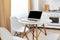 Round white table with laptop with blank screen for advertisement and smart phone on it, workspace for freelancer at home in light