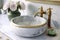 round white wash basin with brass faucet and towel ring on marble countertop