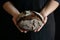 Round whole dark bread in baker\'s hand