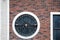 Round window with iron lattice on the brick wall with beautiful stonework