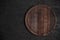 Round wooden cutting board on black table. Top view of empty kitchen trendy rustic wooden tray.