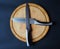 Round wooden cutting board with two crossed knives