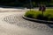 Roundabout of gray granite cubes closer to the center. beveled concrete curbs with flowers and grass in the middle of the circle.