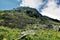 The rounded top of the mountain against a blue sky with white clouds.