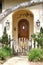 Rounded wooden door recessed in a porch provides an inviting entry way to a charming cottage in Carmel-by-the-Sea, CA.