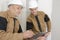 Roup smiling builders with clipboard and electrical panel indoors