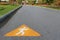 Route symbol for running written on the asphalt road with blurry people jogging in the public park