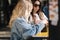 Daily routines of two female colleagues on lunch break. Blond and brown-haired girls speak outdoors during lunch